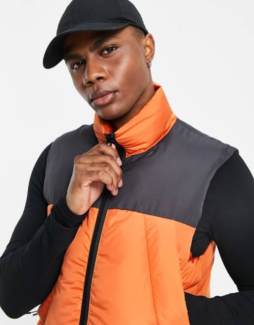 ASOS DESIGN puffer quilted vest in orange with black cut and sew panel ASOS