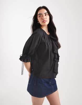 ruffle front top with pleated detailing and tie front in black