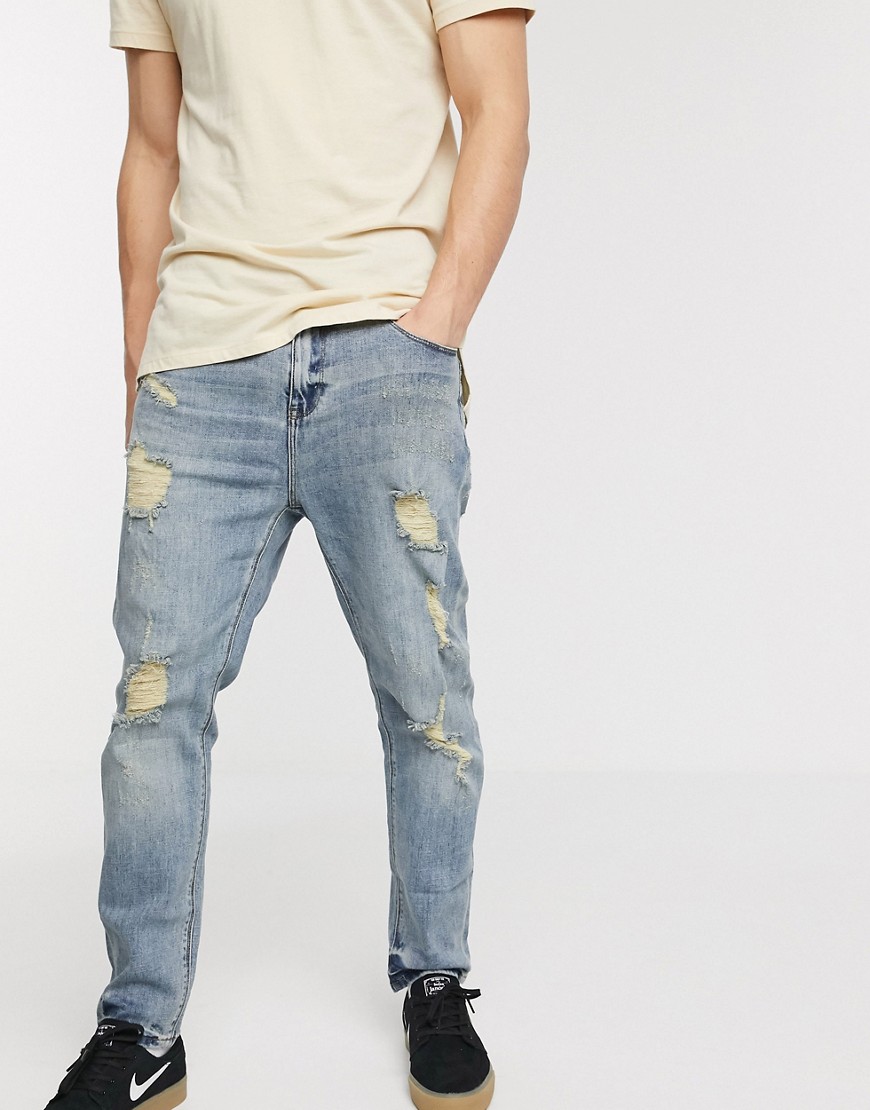 ASOS DESIGN - Ruimvallende jeans met smaltoelopende pijpen en grote scheuren in lichtblauwe wassing