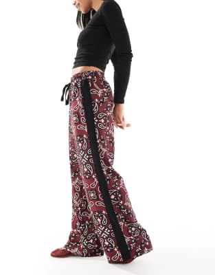 ASOS DESIGN - Schlupfhose in dunklem Kirschrot mit Kontrastbahn und Bandana-Muster