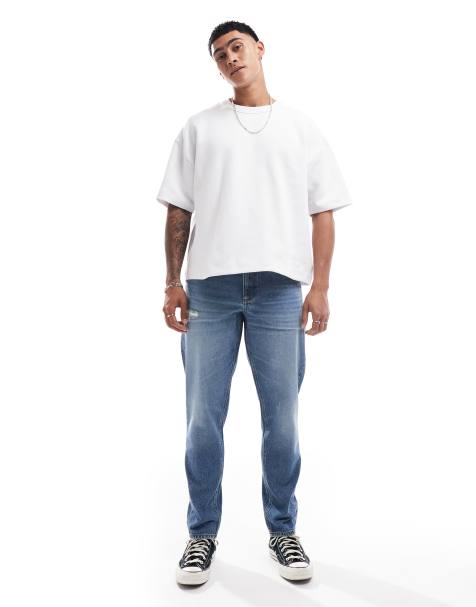 ASOS DESIGN – Schmal zulaufende Jeans in mittelblauer Waschung mit Abnutzungen - view 1