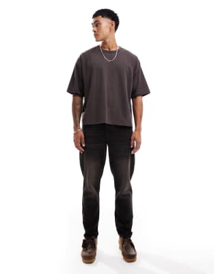 ASOS DESIGN – Schmal zulaufende Jeans in verwaschenem Schwarz mit braunem Farbstich - view 1