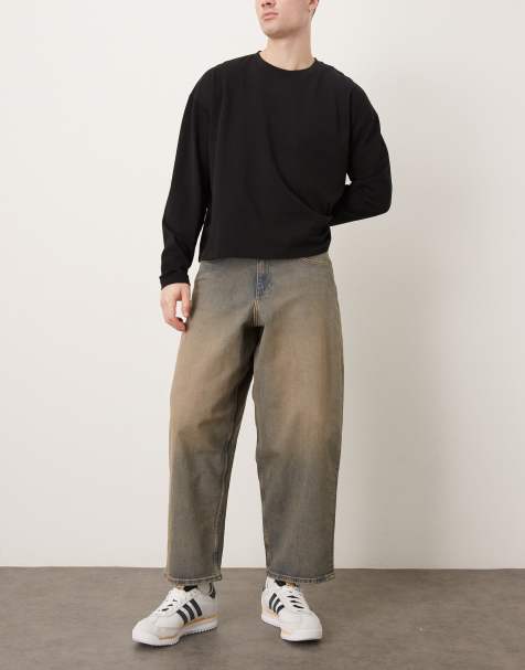 ASOS DESIGN – Schmal zulaufende Oversize-Jeans in mittelblauer Waschung mit braunem Farbstich - view 1