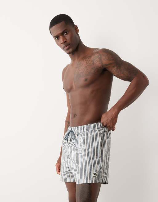 ASOS DESIGN seersucker stripe swim shorts in short length with badge in navy, 2 of 5