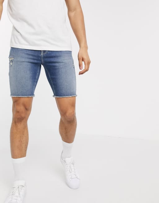 ASOS DESIGN skinny denim shorts with power stretch in mid wash blue with raw hem and abrasions