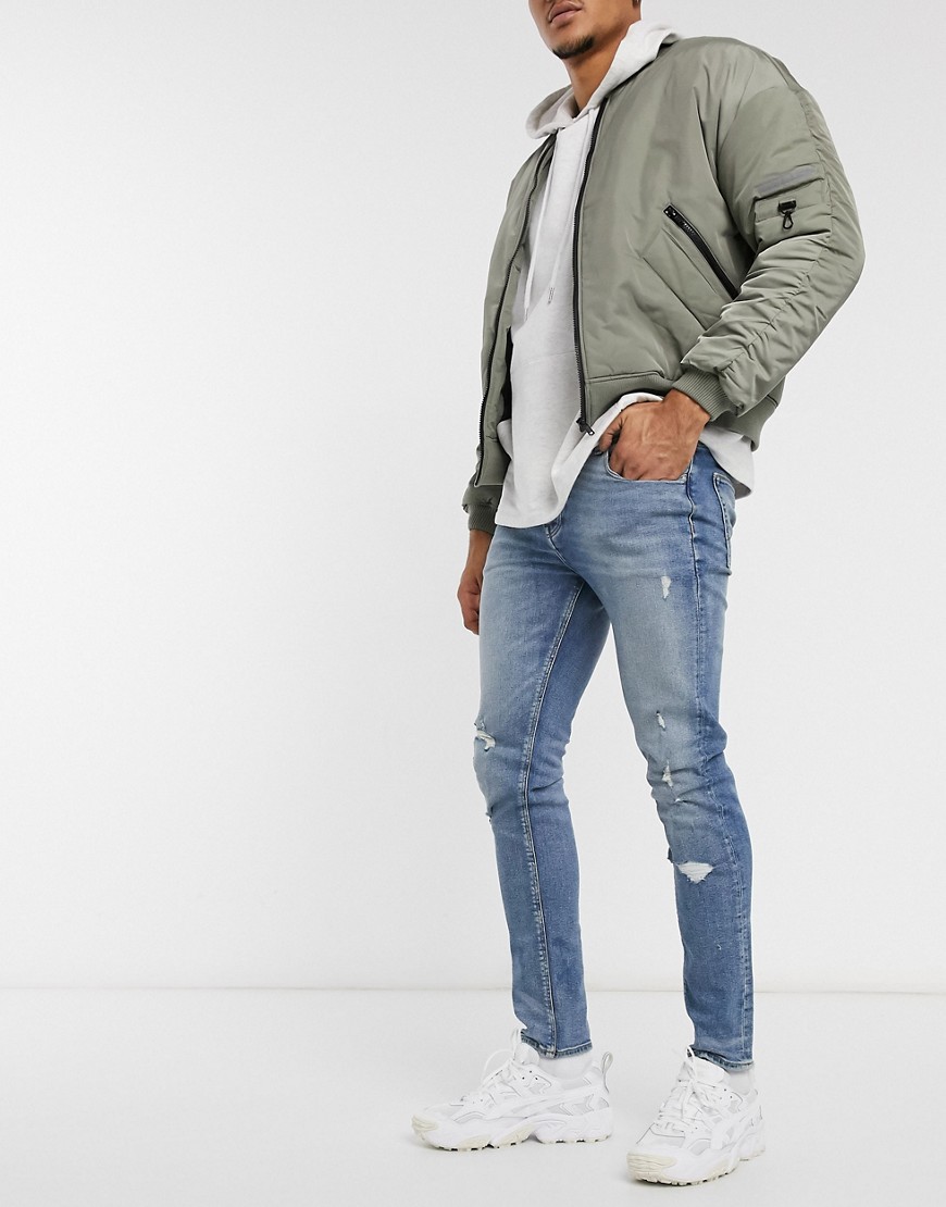 ASOS DESIGN skinny jeans in tinted light wash blue with rips-Blues