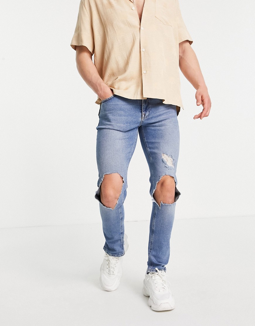 ASOS DESIGN skinny jeans with knee rips and destroyed hem in mid wash blue-Blues