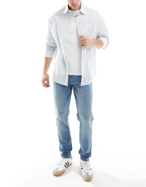 ASOS DESIGN skinny jeans with yellow tint in mid wash blue