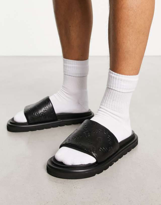 ASOS DESIGN sliders in black faux Leather with monogram emboss