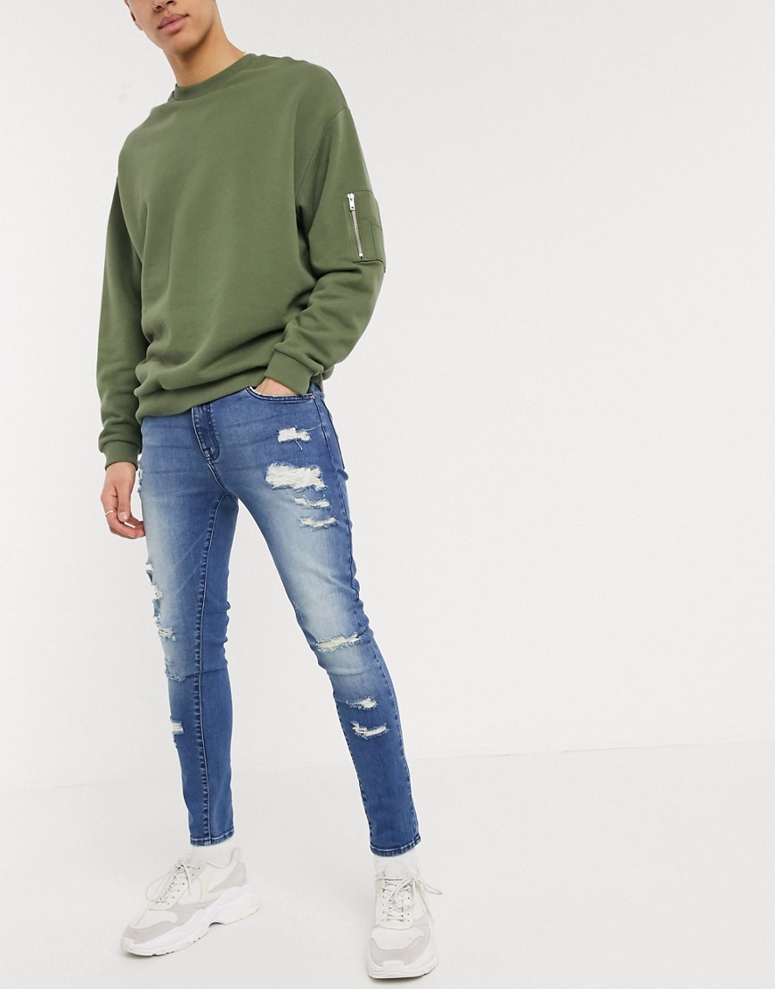ASOS DESIGN spray on jeans in power stretch with heavy rips in mid wash blue
