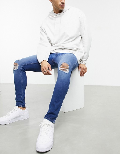 ASOS DESIGN spray on jeans in power stretch with 'less thirsty' wash in mid blue with knee rips