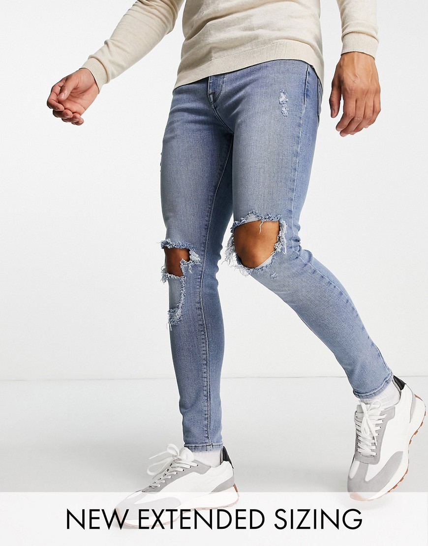 ASOS DESIGN - Spray-on jeans met power stretch, kniescheuren en slijtageplekken in middenblauwe wassing