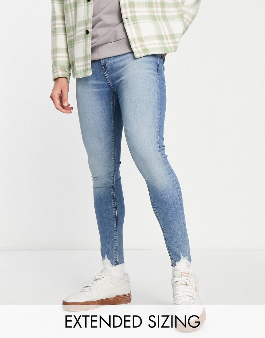 ASOS DESIGN spray on jeans with power stretch in light wash with ripped hem detail-Blue