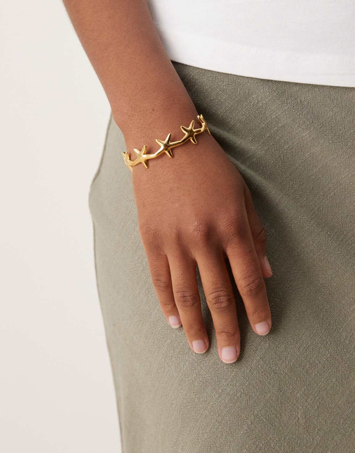 ASOS DESIGN stainless steel waterproof cuff bracelet with mini starfish detail in gold tone