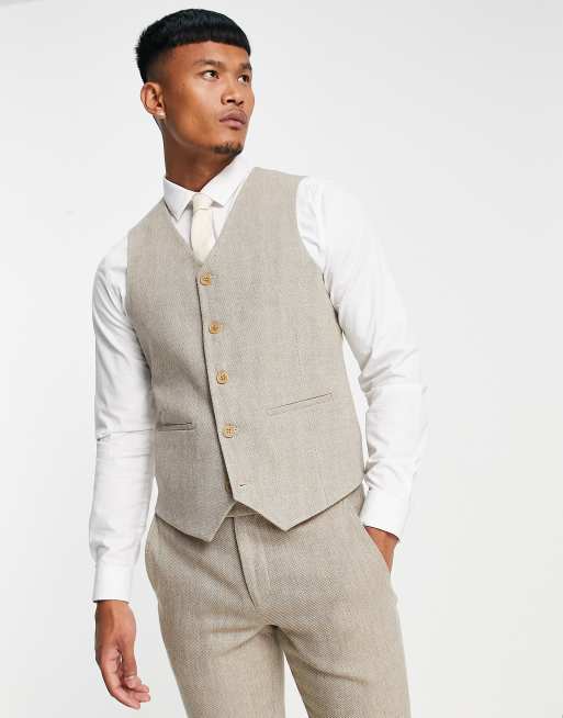 A guest wears a white tweed buttoned V-neck gilet jacket, a beige