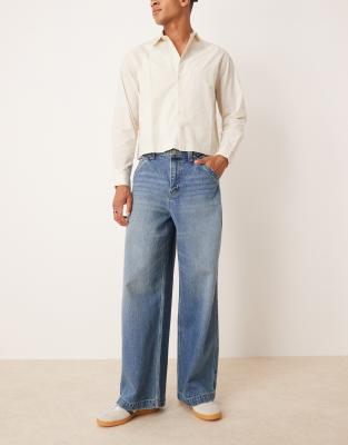 ASOS DESIGN – Super weite Jeans in mittelblauer Waschung mit bestickter Gesäßtasche - view 1