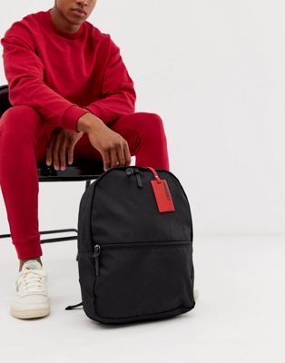 ASOS DESIGN – Svart ryggsäck med röd bagagelapp