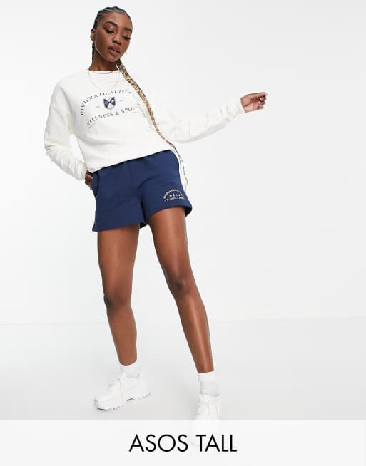 ASOS DESIGN Tall - Trainingspak van sweatstof met short met omgeslagen taille en grafische Riviera opdruk in marineblauw/crème