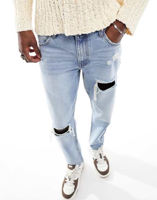 ASOS DESIGN tapered fit jeans with rips in light wash blue