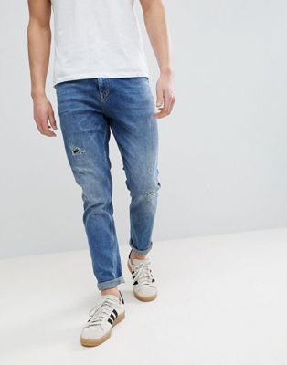 ASOS DESIGN tapered jeans in dark wash with rip & repair-Blue