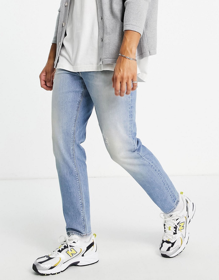 ASOS DESIGN tapered jeans in 'less thirsty' light wash with abrasions-Blues
