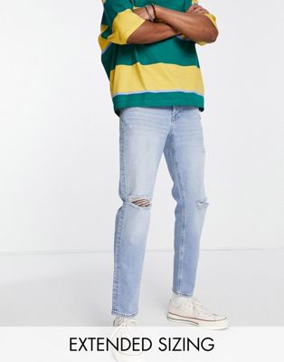 ASOS DESIGN tapered jeans in mid vintage wash with knee rips and abrasions