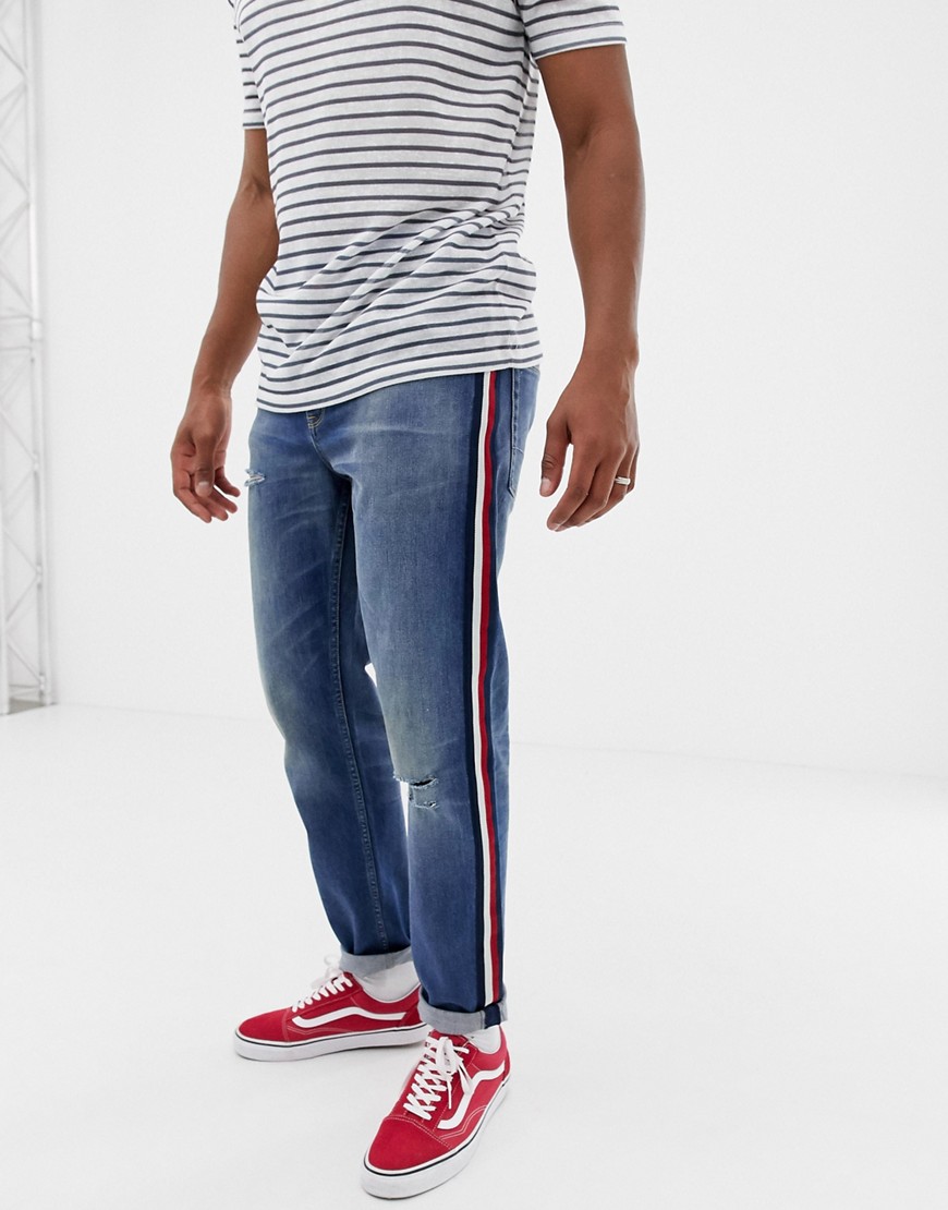ASOS DESIGN tapered jeans in mid wash blue with red side stripe