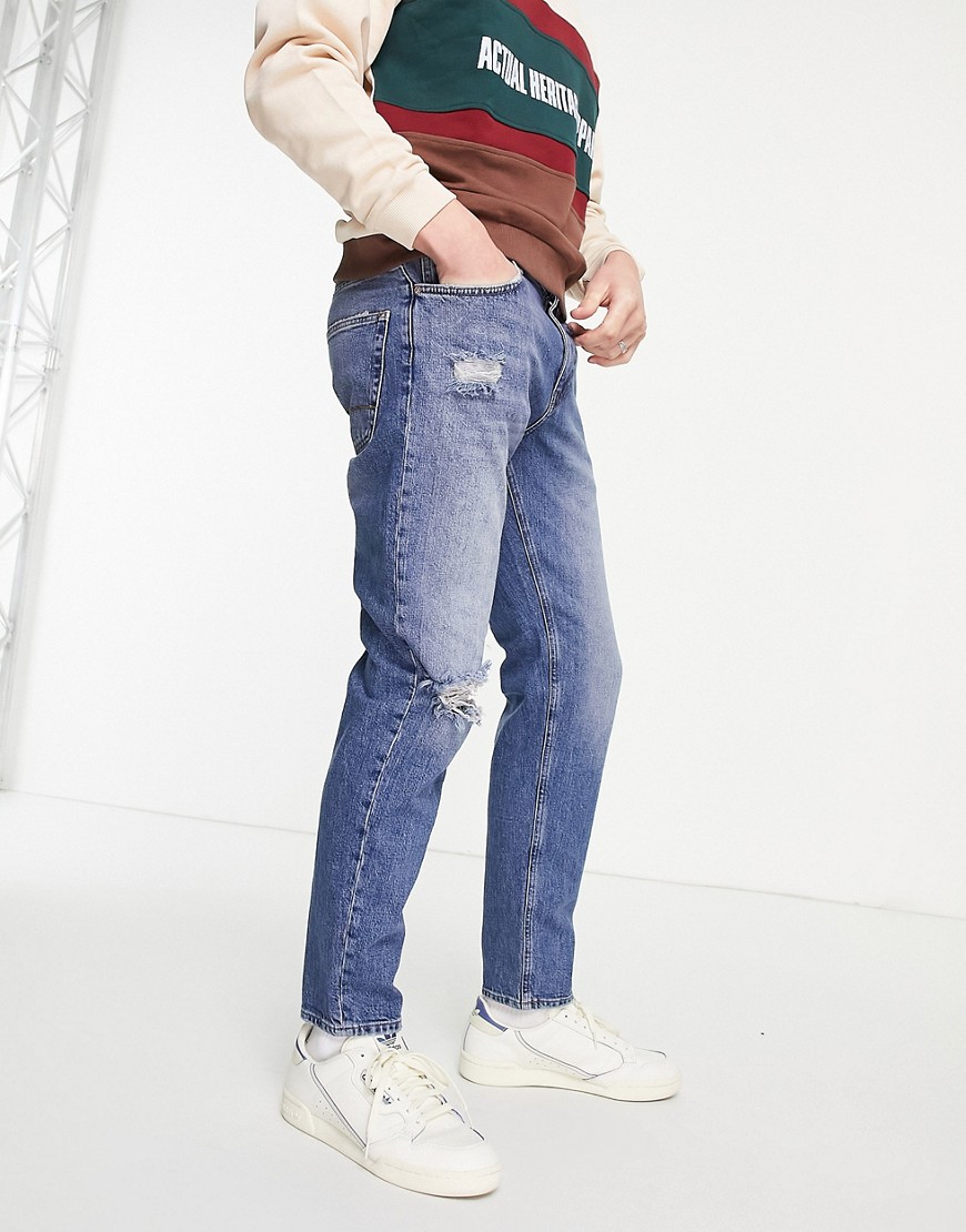ASOS DESIGN tapered jeans in vintage mid wash with rips-Blues