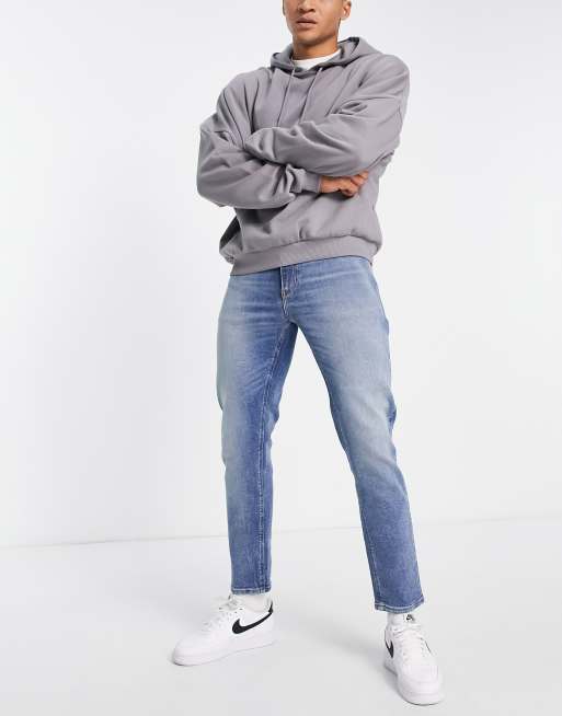 ASOS DESIGN - Tapered jeans med stretch i tonet mellemvask