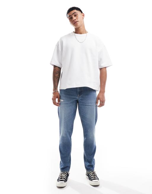 ASOS DESIGN tapered jeans with abrasions in mid wash blue