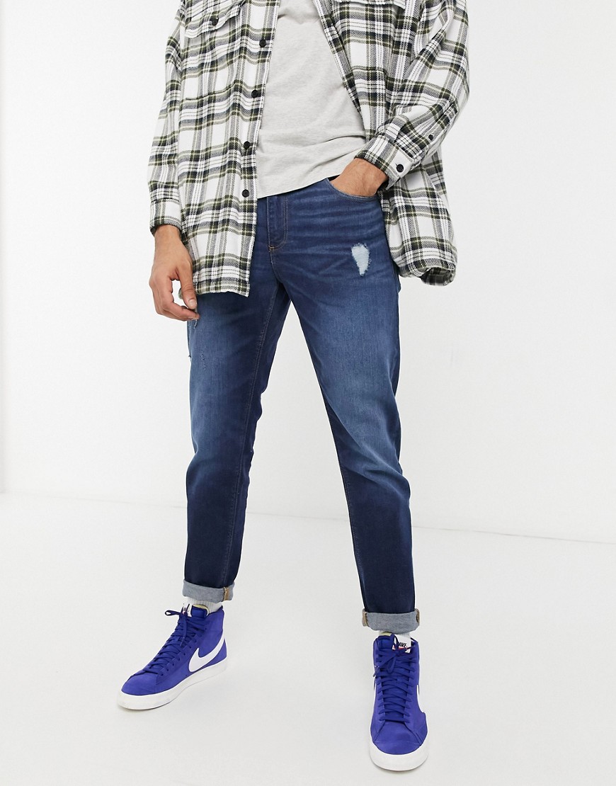 ASOS DESIGN tapered jeans with 'less thirsty' wash in dark blue with abrasions