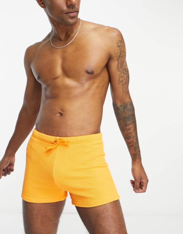 ASOS DESIGN textured swim trunks in orange