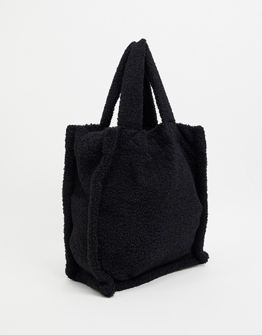 ASOS DESIGN tote bag in black borg with shoulder strap and grab handle