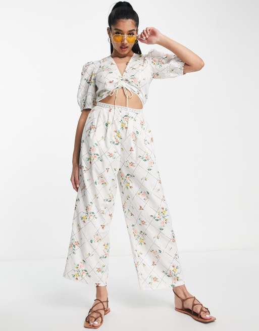 ASOS DESIGN - Tuta jumpsuit con inserti in pizzo e cut-out con maniche a sbuffo e stampa a fiori a griglia