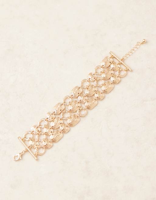 ASOS DESIGN wide bracelet with swirly design in gold tone