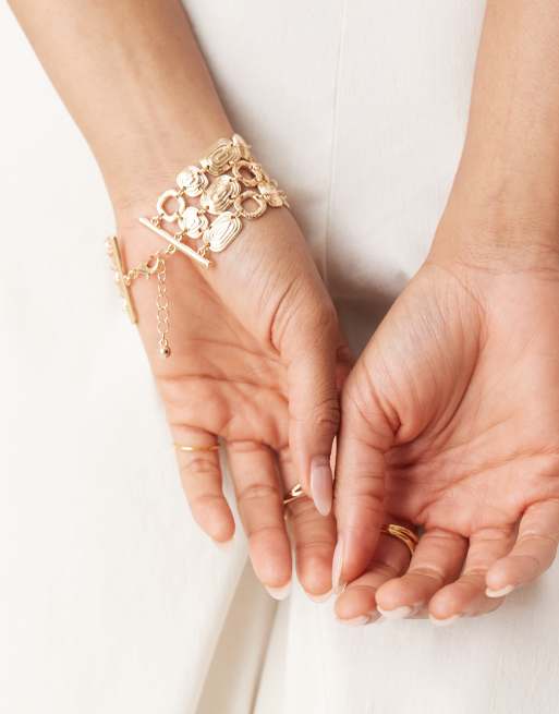 ASOS DESIGN wide bracelet with swirly design in gold tone