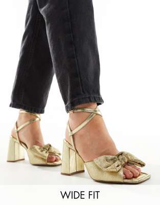 ASOS DESIGN Wide Fit - Hitched - Sandalen in Gold mit mittelhohem Blockabsatz und Schleifendetail, weite Passform-Goldfa...