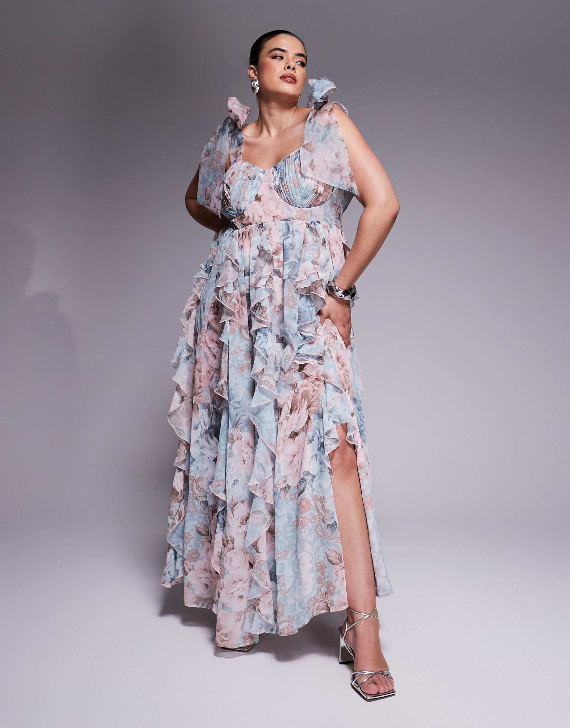 A light blue and lavender floral plus-size maxi dress with bustier cups, ruffles, and adjustable bow straps