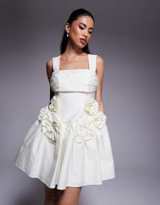ASOS LUXE - Tailliertes Minikleid aus Baumwollsatin in Buttermilchgelb mit plissierter Brustpartie und Ansteckblumendeta...