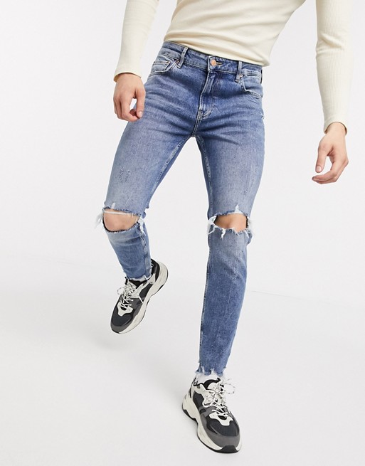 Bershka skinny jeans with knee rips and raw hem in mid wash blue