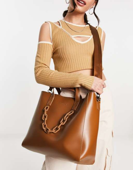 Bolso tote color tostado con detalle de cadena en el mismo tono y correa bandolera de Claudia Canova