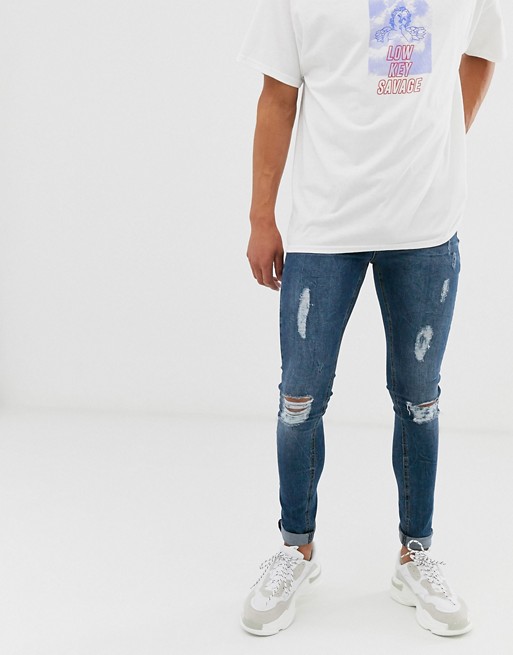 boohooMAN spray on jeans with distressing in blue wash