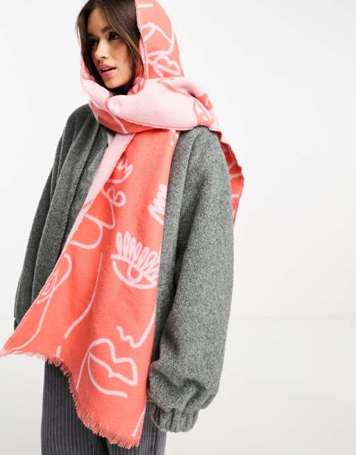 Bufanda rosa y roja tipo manta con diseño de rostros de jacquard de ASOS DESIGN 