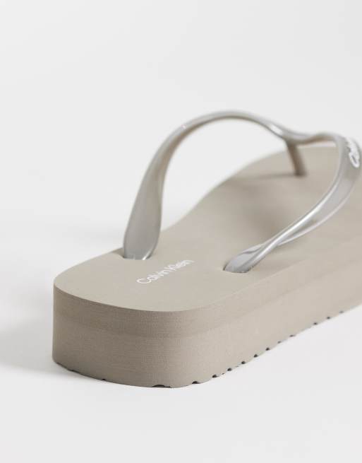 Calvin Klein Jeans – Zehensteg-Sandalen in Metallic-Cremeweiß mit flacher Plateausohle, 4 von 4