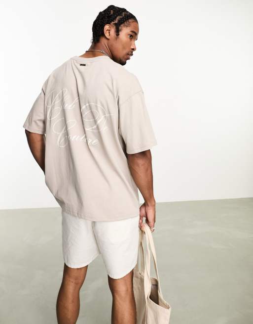 Camiseta beis con texto estampado en el pecho y la espalda de The Couture Club