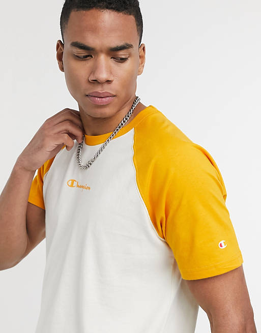 Camiseta blanca hueso con mangas raglán naranjas y logo de Champion