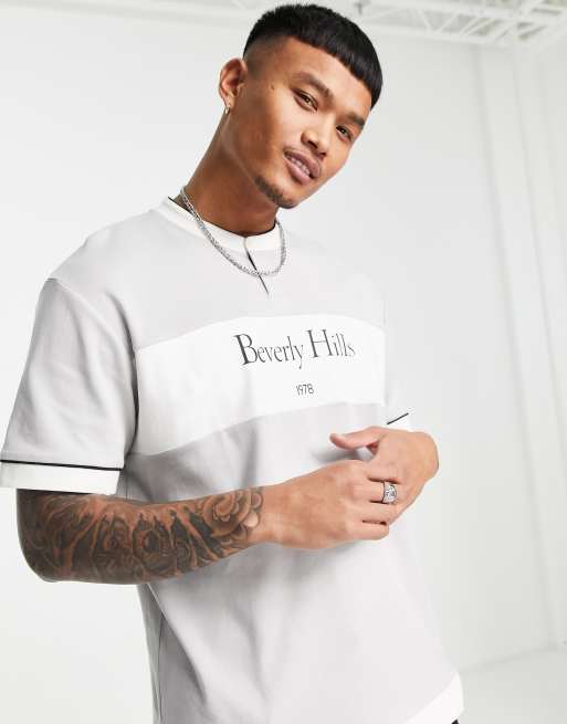 Camiseta gris con diseño de paneles, botón en el cuello y estampado 