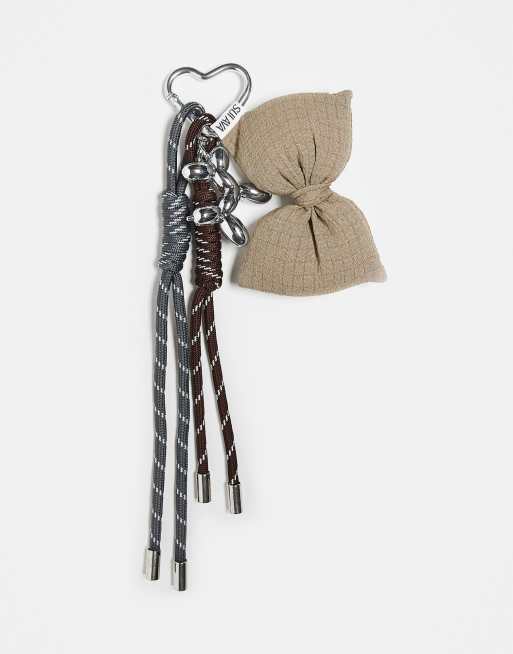 Charm para bolso plateado con detalle de lazo y cuerdas de Sui Ava