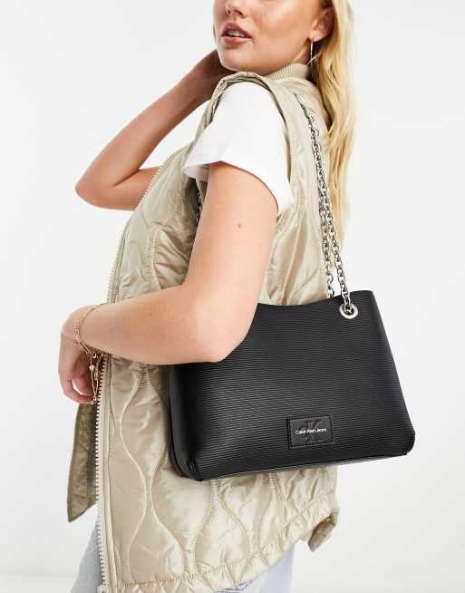 CK Jeans – Geformte Tasche in Schwarz mit Umschlagklappe und Kettenriemen