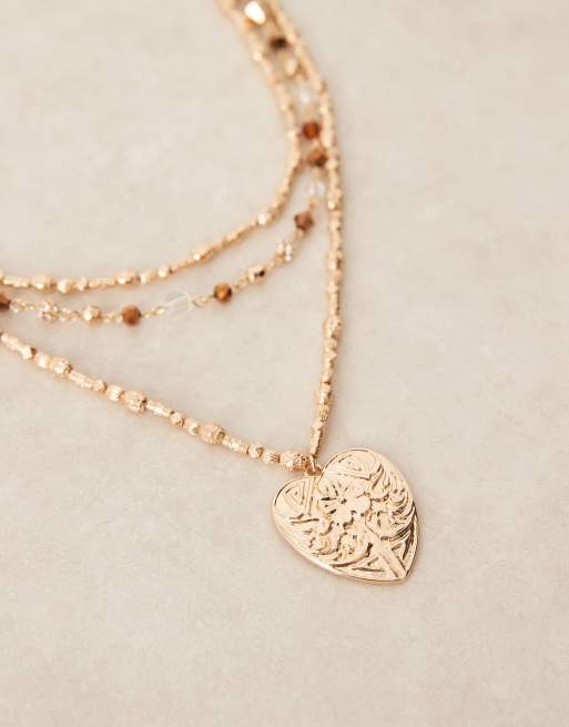 Collar dorado de varias hileras con colgante grande de corazón repujado y cuentas marrones de ASOS DESIGN, 2 de 3